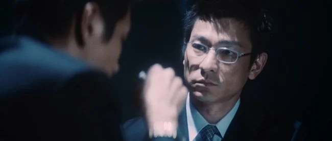 《无间道》(2002 第一部)大B角色参考图片;林家栋戴眼镜与刘健明交谈,右侧正面